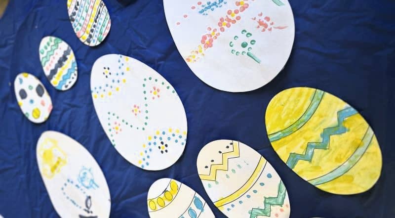 Easter craft for kids. A selection of colourful cardboard Easter eggs decorated using a cotton bud painting technique.