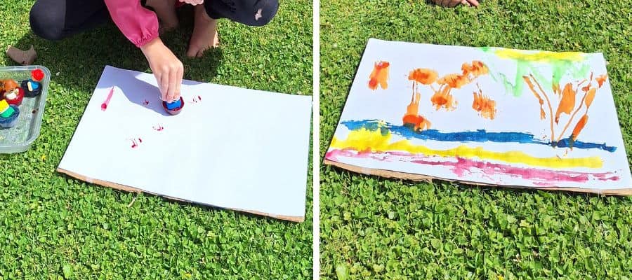 A preschooler painting on card with coloured ice paints